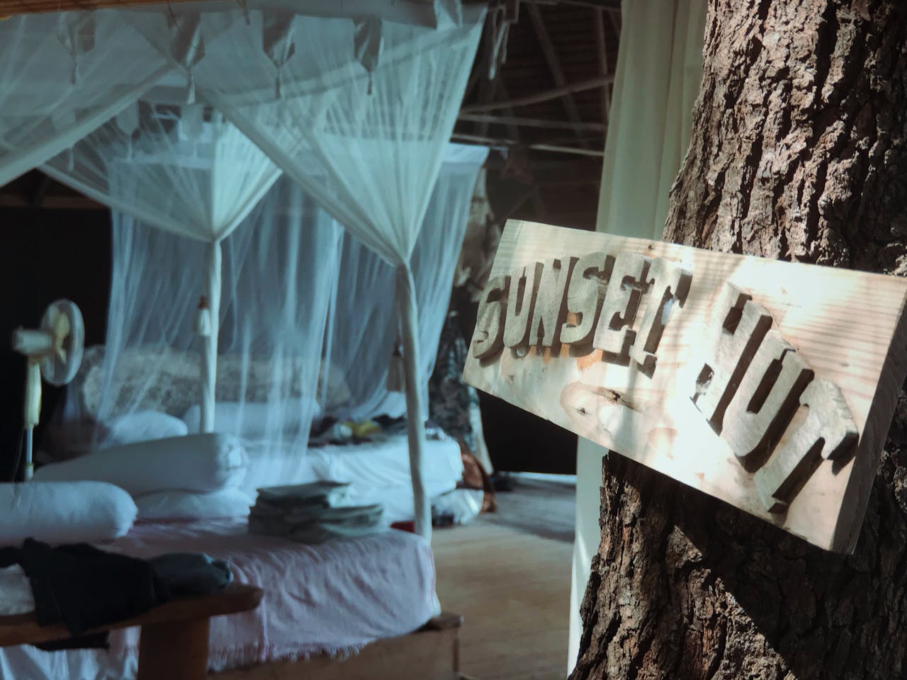 Inviting canopy bed in a rustic sunset hut, perfect for relaxing in tropical Indonesia.